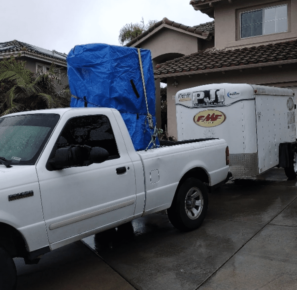 A white truck loaded with big furniture on the back